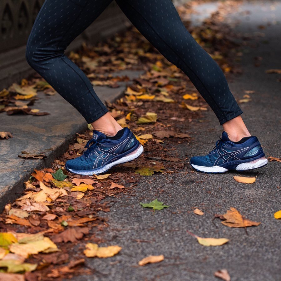 ragazza con leggins neri e asics gel nimbus 22 blu fa stretching