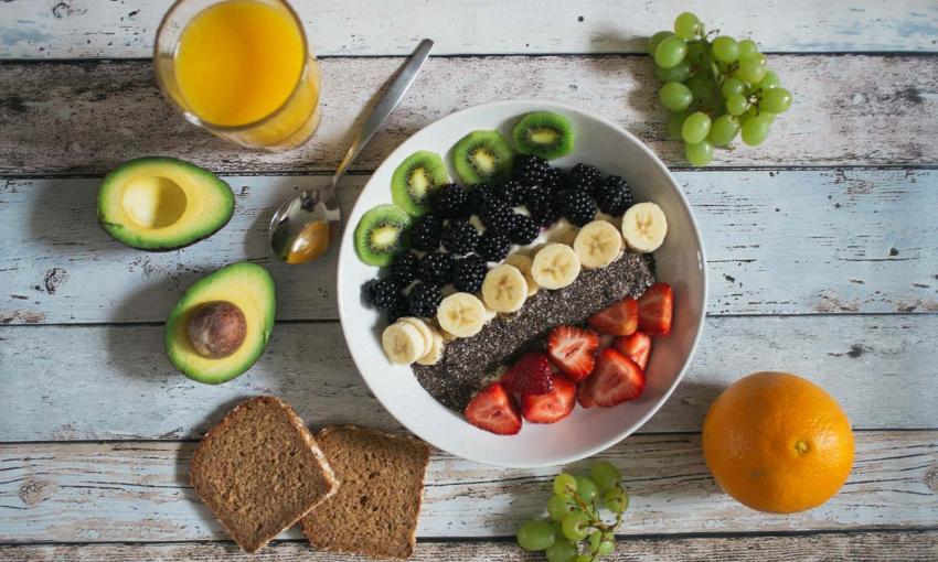 bowl con frutta mista, due fette di pane, avocado, arancia e spremuta