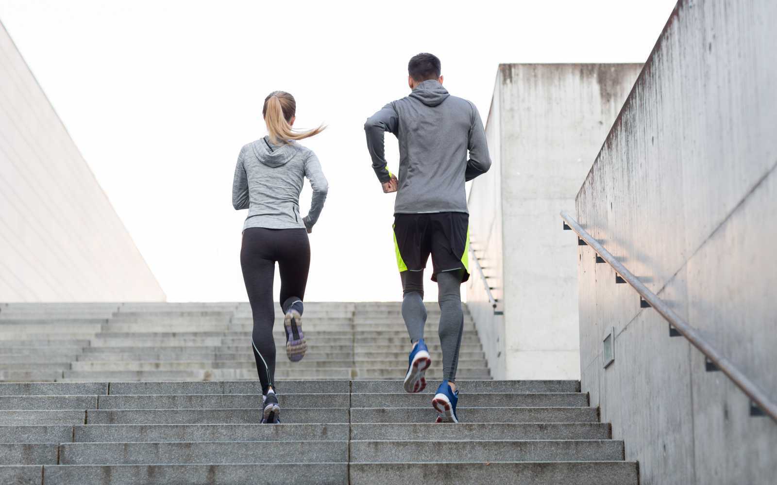 2 runner uomo e donna corrono in salita su scale