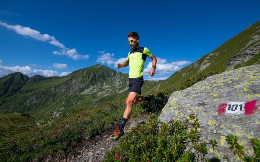 runner con t-shirt tecnica, pantaloncini e scarpe da trail corre in montagna