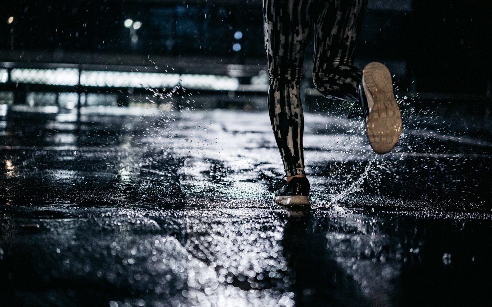 ragazza corre con la pioggia su asfalto bagnato